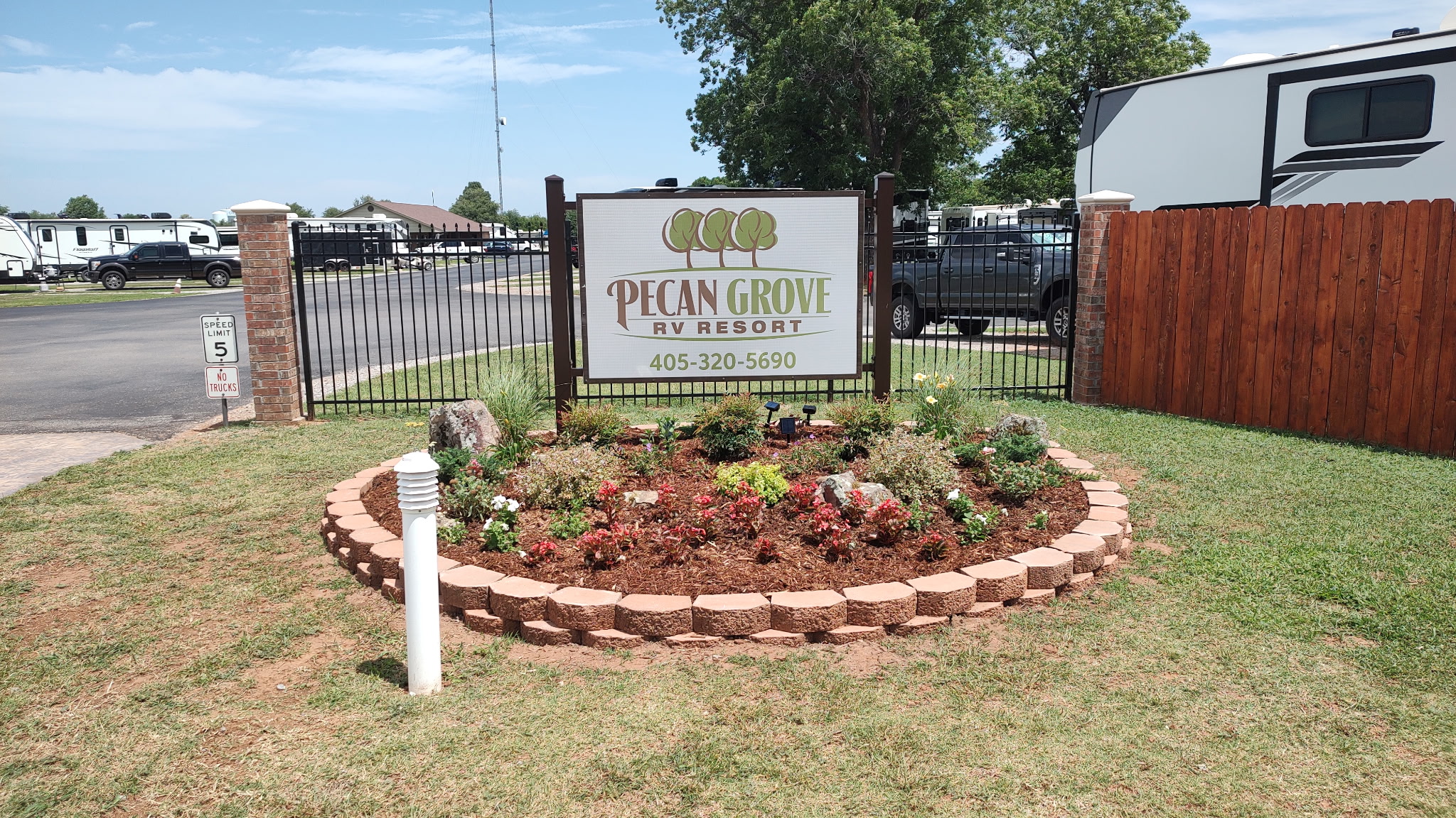 The Pecan Grove RV Resort entrance sign and flower bed on a clear day